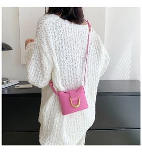 Pink leather mini crossbody bag with gold U-shaped buckle shown on a model from the back