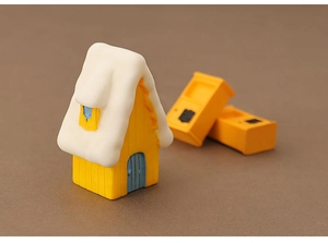 Macro shot of miniature yellow Christmas house with snow roof and blue door