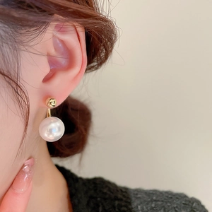 Macro close-up of a model wearing a gold plated pearl earring with elegant French vintage style