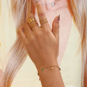 Gold jewelry set with layered rings and a multi-colored square zircon charm bracelet