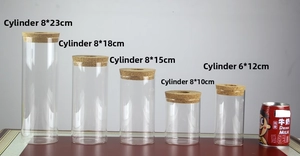 Five cylindrical glass vases of varied heights with cork stoppers and size comparison