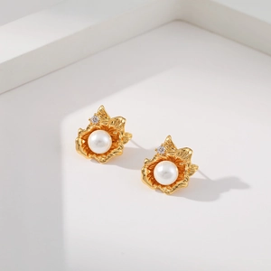 Irregular geometric floral gold earrings with white pearl and diamond accents on white background