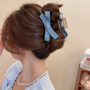 Detail of blue denim bow hair claw clip with colorful polka dots on a stylish model