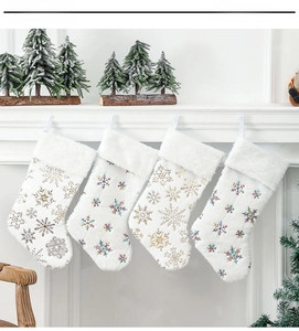 Lot de 4 chaussettes de Noël en peluche blanche avec flocons dorés et colorés.