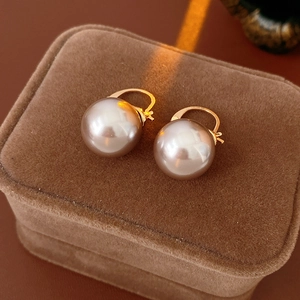 Detail shot of vintage pearl hoop earrings on a velvet jewelry box with warm lighting