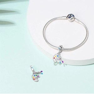 Artistic silver charm bracelet featuring a colorful painter palette and heart-shaped gemstone clasp