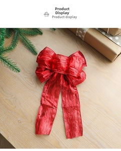 Large red glitter Christmas bow with metallic texture on rustic wooden surface with gifts