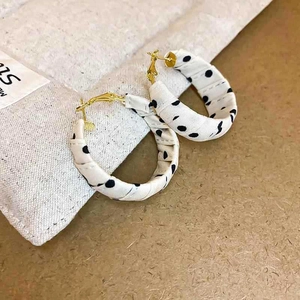 Detail shot of black polka dot fabric wrapped hoop earrings with gold metal hooks