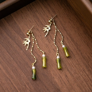 Detail of long gold tassel earrings featuring green bamboo nodes and white pearl beads