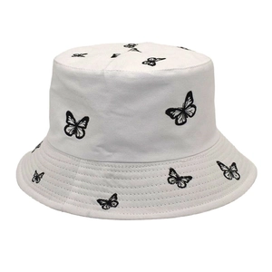 Détail de la broderie papillon noire sur un chapeau bob réversible en coton blanc
