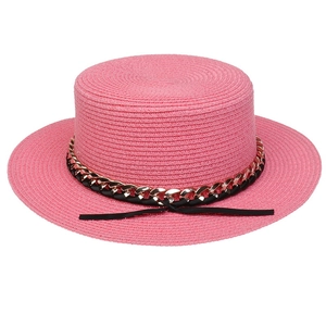 Detailed texture of pink straw hat featuring a gold chain and black ribbon bow