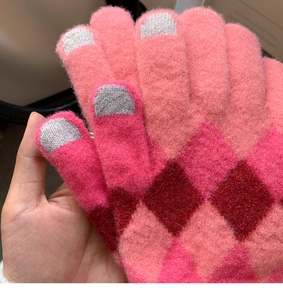 Close-up of pink knit gloves featuring red diamond patterns and grey touchscreen fingertips