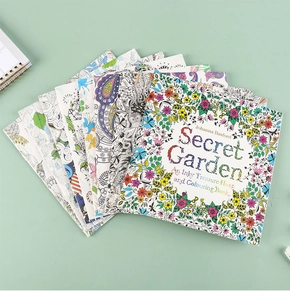 Detail of Secret Garden coloring books stacked on a green desk showing floral patterns