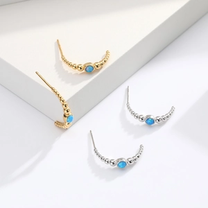 Macro detail of gold and silver curved bead earrings featuring round blue opal stones