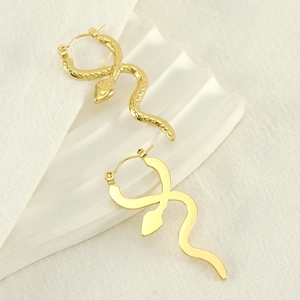 Snake-shaped gold hoop earrings with polished and textured scales on white fabric