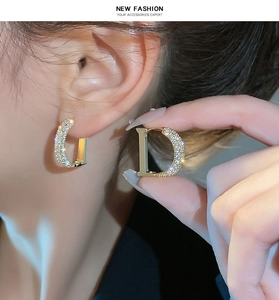 Macro shot of gold plated D-letter earrings featuring sparkling cubic zirconia stones