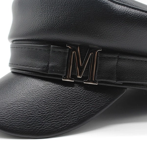 Detailed macro view of black PU leather baker boy hat with silver metal M emblem