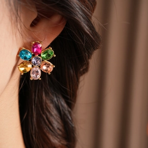 Close-up of vintage flower stud earring with gold metal and colorful crystals on a model