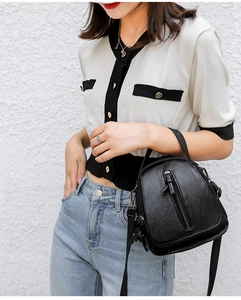 Detail of black PU leather crossbody bag with dual zippers and soft textured finish