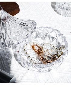 Macro shot of an embossed glass jewelry box containing a pearl necklace and watch