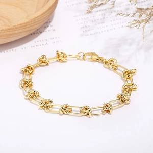 Dettaglio di un bracciale a catena dorata con nodi decorativi e chiusura a moschettone