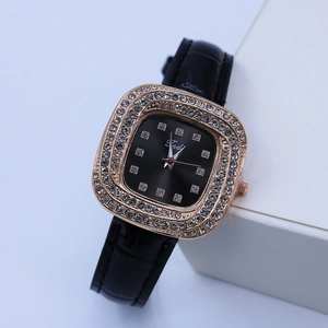 Détail de la montre carrée en or rose sertie de strass avec un bracelet en cuir noir mat