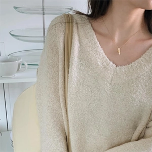 Detail of a minimalist gold knot necklace pendant on a 925 sterling silver chain