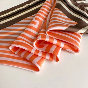 Gros plan du foulard en satin de soie avec rayures géométriques orange et rose vif