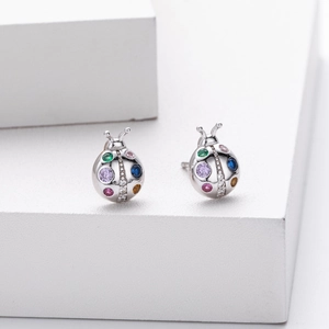 Macro detail of 925 sterling silver ladybug earrings with colorful gemstones and zircons