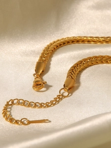 Dettaglio della collana a catena intrecciata dorata con chiusura su seta beige