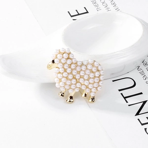 Gros plan d'une broche mouton avec perles blanches et métal doré sur fond blanc