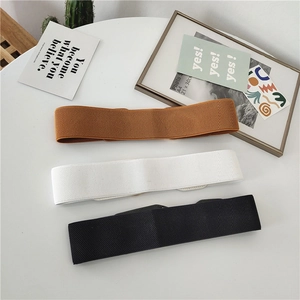 Detailed texture of elastic wide belts in black, brown, and white with oval metal buckles