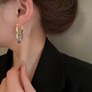 Close-up of model wearing two-tone gold and silver chain link huggie hoop earrings