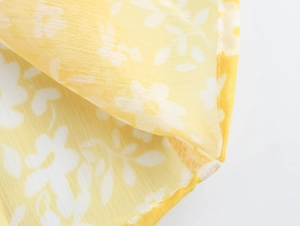 Detail of yellow floral chiffon fabric showing delicate stitching and sheer texture