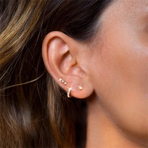 Detailed view of three gold zircon earrings set worn on ear with sparkling studs and hoop