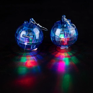 Close-up of glowing blue sphere earrings with RGB LED lights inside on black surface