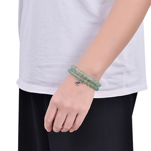 Green aventurine beaded bracelet with silver heart charm on female wrist