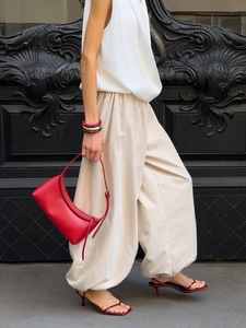 Fashion street style detail of beige cotton harem pants paired with a red handbag