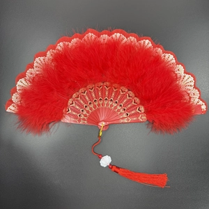 Close-up of red feather folding fan with gold patterned ribs and matching tassel