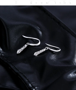 Macro shot of silver drop earrings with D color moissanite stones on black leather