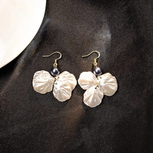 Detail of petal pearl earrings with grey pearls on elegant black silk background
