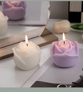 Macro view of burning white and purple rose shaped scented candles in a cozy home setting
