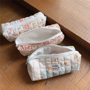 Detailed view of quilted cotton pencil cases in various floral patterns with metal zippers