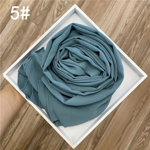 Vue détaillée du tissu en mousseline avec paillettes dorées dans un ton bleu poudré élégant
