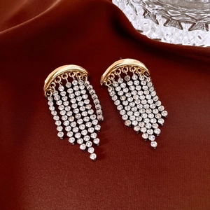 Gros plan détaillé de boucles d'oreilles à pompons dorés avec strass sur tissu en soie