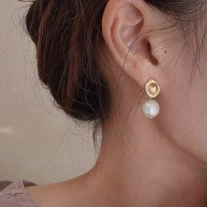 Close-up of Baroque pearl earrings with irregular gold metal studs on female model