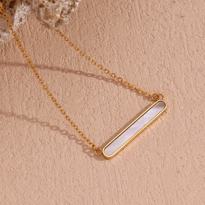 Vue macro détaillée du pendentif barre plaqué or 18K avec incrustation de nacre blanche