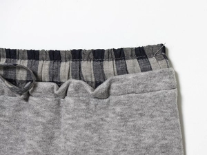 Detail view of grey knit skirt waistband with blue plaid lining and elastic design