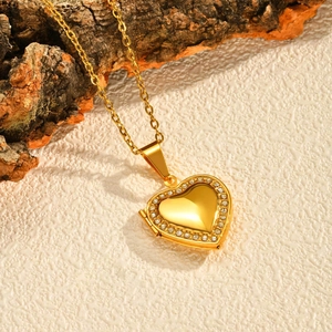 Macro shot of gold heart locket necklace with sparkling rhinestones on textured surface