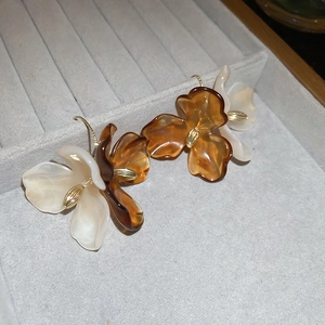 Close-up of amber and cream resin flower earrings with gold metal centers in a tray
